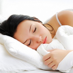 Woman sleeping in white bed with white sheets